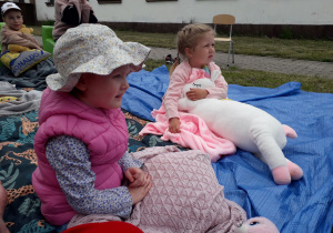 Dziewczynki w plenerowej strefie czytelniczej podczas akcji "Czytanie na polanie".