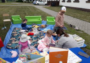 Dzieci w plenerowej strefie czytelniczej oglądają różne książeczki.