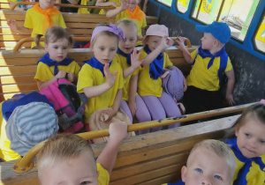 Dzieci siedzą w wagonie kolejki, która jedzie po terenie zoo