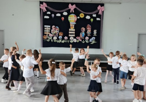 Przedszkolaki obracają się w parach podczas tańca.