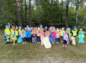 Dzieci pozują do zdjęcia grupowego na tle lasu
