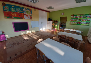 sala z stolikami, gazetką tematyczną i kącikiem przyrody w grupie