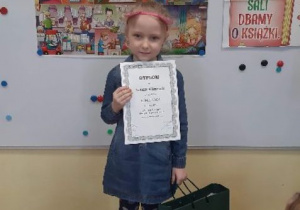 Dziewczynka trzymająca dyplom i nagrody