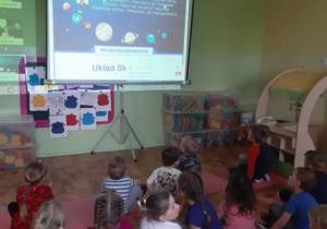 Grupa młodsza oglądająca prezentację multimedialną o kosmosie