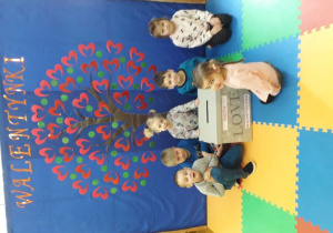 Dzieci na tle dekoracji walentynkowej otwierają skrzynkę walentynkową.