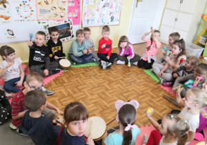 Dzieci siedzące w kole i grające na instrumentach