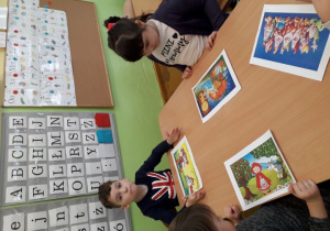 Dzieci przy stoliku prezentują wykonane baśniowe puzzle.