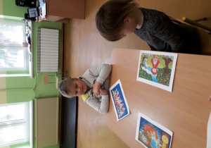 Chłopiec i dziewczynka przy stoliku prezentują swoje baśniowe puzzle..