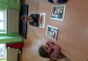 Dzieci przy stoliku prezentują wykonane baśniowe puzzle.