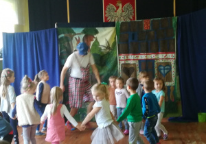 Zdjęcie przedstawia dzieci, które tańczą z aktorem.