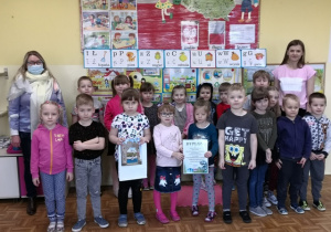Przedszkolaki z nauczycielem i panią z biblioteki trzymające nagrodę w konkursie