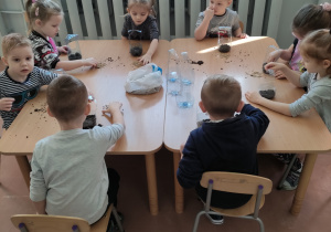 Grupa dzieci przy stoliku sieje owies.