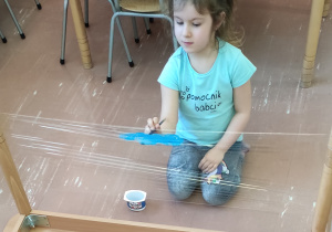 Dziecko maluje na folii spożywczej.