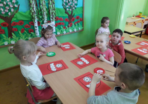 Dzieci przy stolikach wykonują herb Gminy Wartkowice.