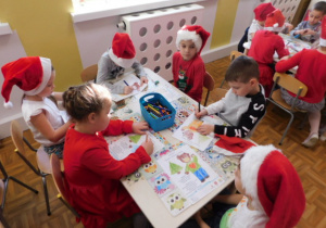 Dzieci siedzące przy stolikach i kolorujące obrazki.