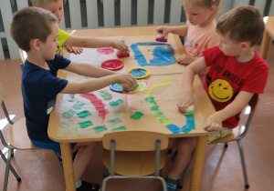 Dzieci malują gąbką.