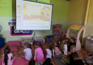 Dzieci oglądające prezentację multimedialną o bezpiecznym spędzaniu wakacji