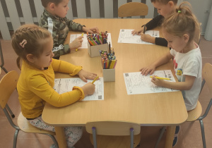 Dzieci wykonują zadanie przy stolikach.