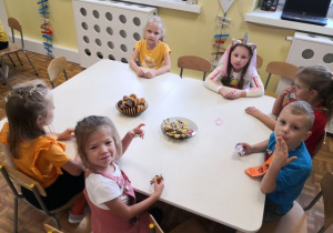 Grupa 5,6-latków siedząca przy stolikach i częstująca się słodkościami