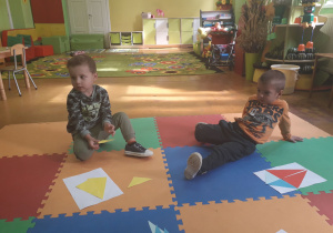 Dzieci na kolorowych matach układają latawiec z trójkątów.