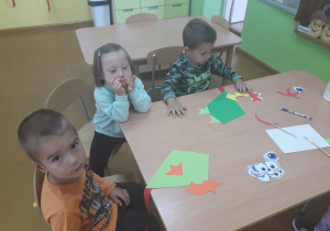 Dzieciaki przy stolikach konstruują latawce z kolorowych elementów.