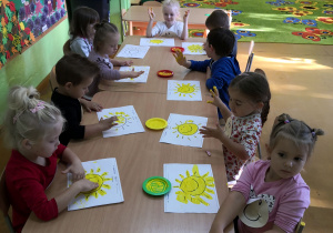 Dzieci malują farbami słoneczko.