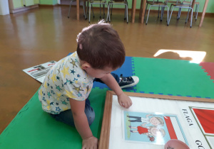 Chłopiec przypina ilustracje na tablicy tematycznej.