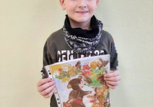 Chłopiec prezentujący pracę na konkurs plastyczny „Przygody Misia Uszatka ”