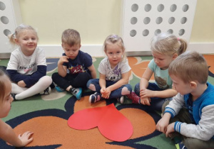 Dzieci siedzące na dywanie i losujące imiona z serca