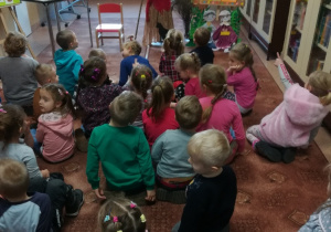 Przedszkolaki siedzą na dywanie i słuchają bajek.