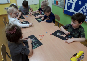 Dzieci rysują na czarnym kartonie fajerwerki.
