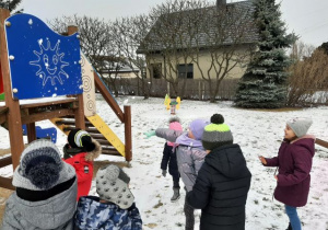 Przedszkolaki rzucające śnieżkami na placu zabaw