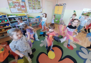 Dzieci trzymające w rękach kolorowe szyfonowe chusty, tańczą do muzyki naśladując lot motyla
