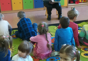 Dzieci słuchają bajek czytanych przez Panią bibliotekarkę.