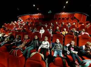 Duża grupa dzieci siedząca w sali kinowej.