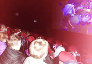 Dzieci siedzące w sali kinowej, oglądające bajkę animowaną.