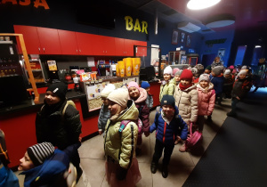 Dzieci ustawione w parach w kinowym holu.