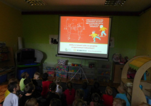 Przedszkolaki oglądające prezentację mulimedialną pt. "Bezpieczne ferie"