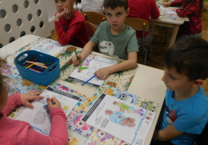 Przedszkolaki kolorujące obrazek dotyczący bezpiecznych ferii.