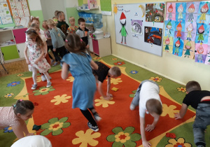 Dzieci ustawione w dwóch rzędach przechodzą na czworakach między woreczkami gimnastycznymi, kolejne ujęcie.