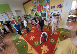 Grupa dzieci 5,6 letnich wykonująca ćwiczenia gimnastyczne z wykorzystaniem szarf.