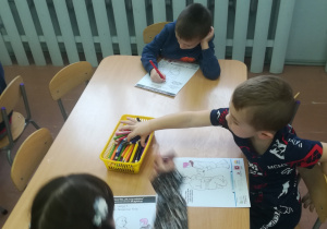 Dzieci kolorują rysunek.