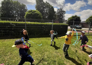 Dzieci na placu zabaw badają kierunek wiatru za pomocą pasków bibuły.