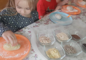 Dzieci z młodszej grupy podczas wygniatania chlebka z ziarnami