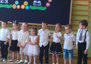 Przedszkolaki ustawione w rzędzie śpiewają piosenkę