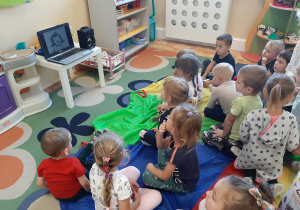 Dzieci z grupy 3,4,5 latków siedzą na dywanie oglądają animację "Kropka".
