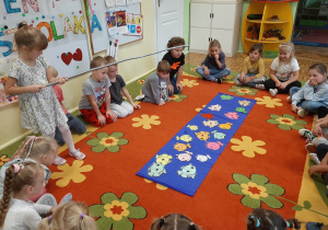 Dzieci uczestniczą w zabawie w języku angielskim. Łowią kolorowe papierowe rybki za pomocą wędki z magnesem. Utrwalają nazwy kolorów w języku angielskim.