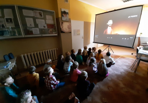 Dzieci oglądają animację o Ignacym Łukasiewiczu na ekranie do rzutnika