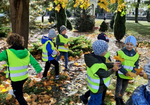 Dzieci podczas spaceru ulicami Wartkowic. Chłopcy zbierają liście klonu.