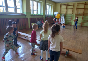 Dzieci stojące w rozscypce na holu przedszkolnym podczas zabawy z piłką